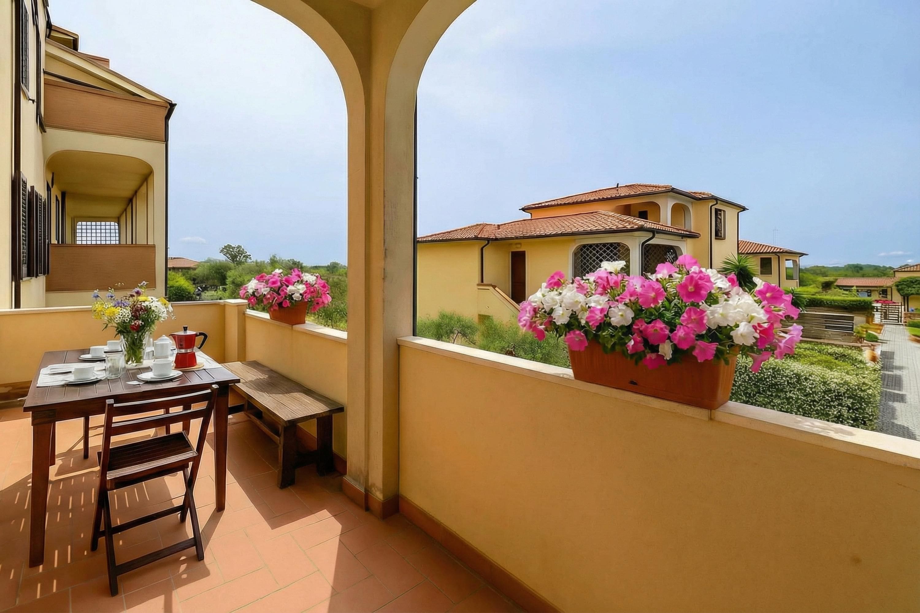 A balcony with a table set for two, a bench, and potted flowers.