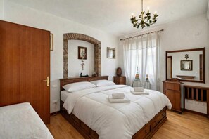 A bedroom with a wooden bed, a stone archway, a chandelier, and a mirror. - Casa di Allegra Terme di Venturina (Campiglia Marittima)
