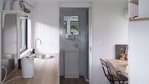 Una cocina compacta con un lavamanos, una ventana pequeña y una mesa de comedor de madera con sillas.
