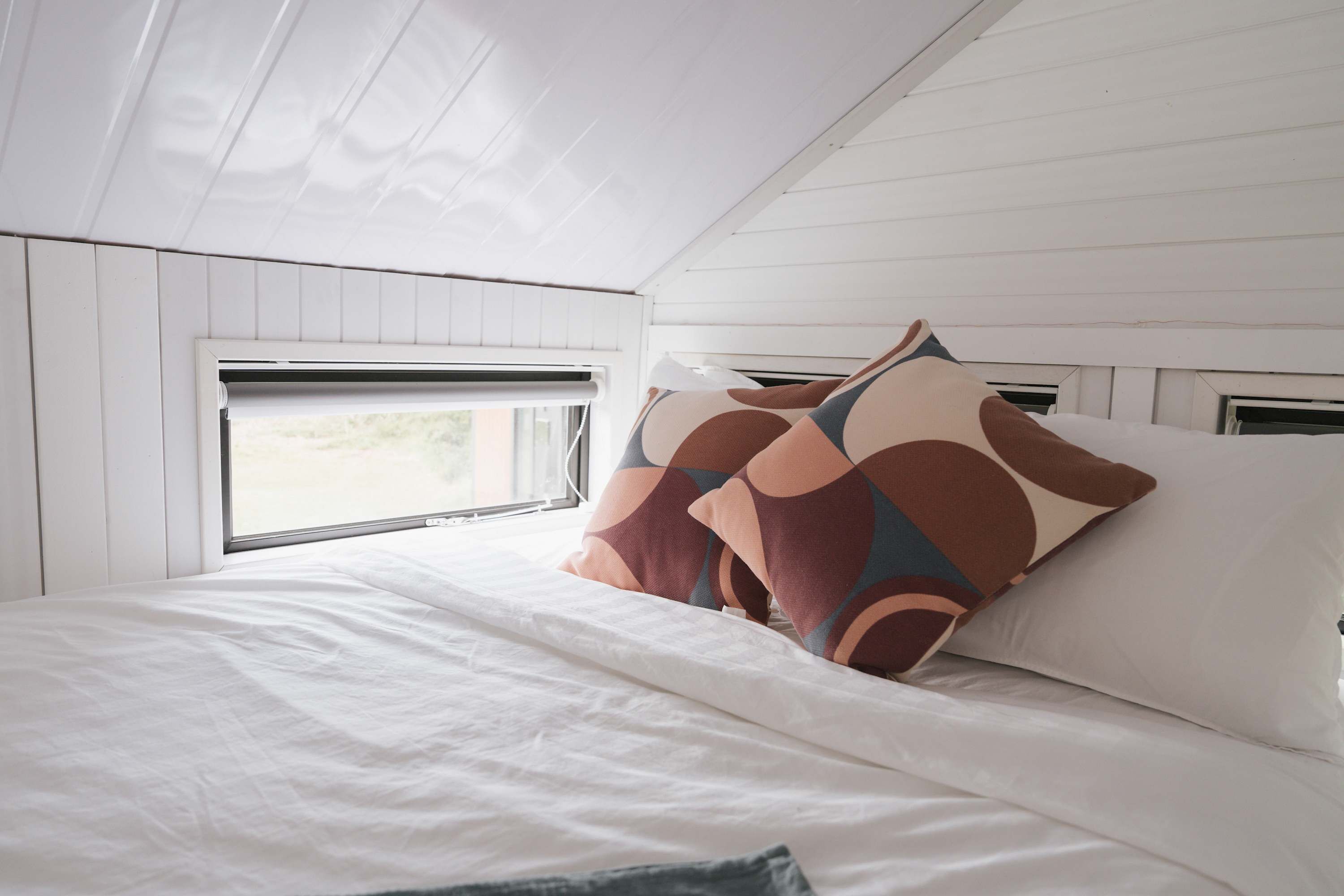 Une chambre à coucher avec un lit, des oreillers, une fenêtre et un plafond blanc.