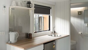Cocina compacta con lavamanos, cafetera y ventana con vistas.