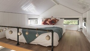 Un dormitorio con cama, ventana y techo con conducto visible.