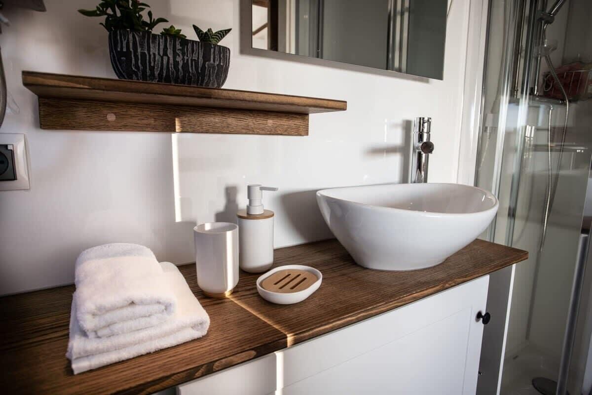 A modern bathroom with a large white basin, wooden countertop, and a mirror above.