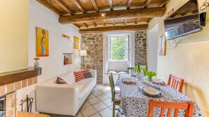 Un coin repas avec une table dressée pour quatre personnes, un canapé blanc et un mur en pierre.