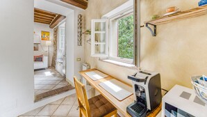 Une cuisine avec une table en bois, une machine à café et une fenêtre donnant sur un paysage verdoyant.
