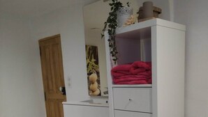 Ein weißer Kleiderschrank mit Spiegel, ein rotes Handtuch und eine kleine Holzschatulle auf dem Boden.