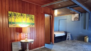 A room with wooden walls, a painting of palm trees, a lamp, a bed, and a ladder. - Minimalist private studio @ Eau Gallie Downtown, spacious in size of 650 sqft.  (Melbourne)