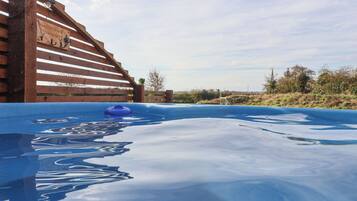 Ein Whirlpool mit einer Holzterrasse und einem Schild, das Besucher willkommen heißt.