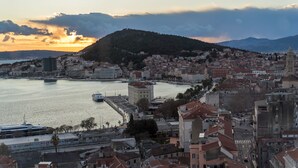 A coastal cityscape with a prominent hill, a waterfront, and a mix of residential and commercial buildings. - Seascape Luxury Rooms (Split)