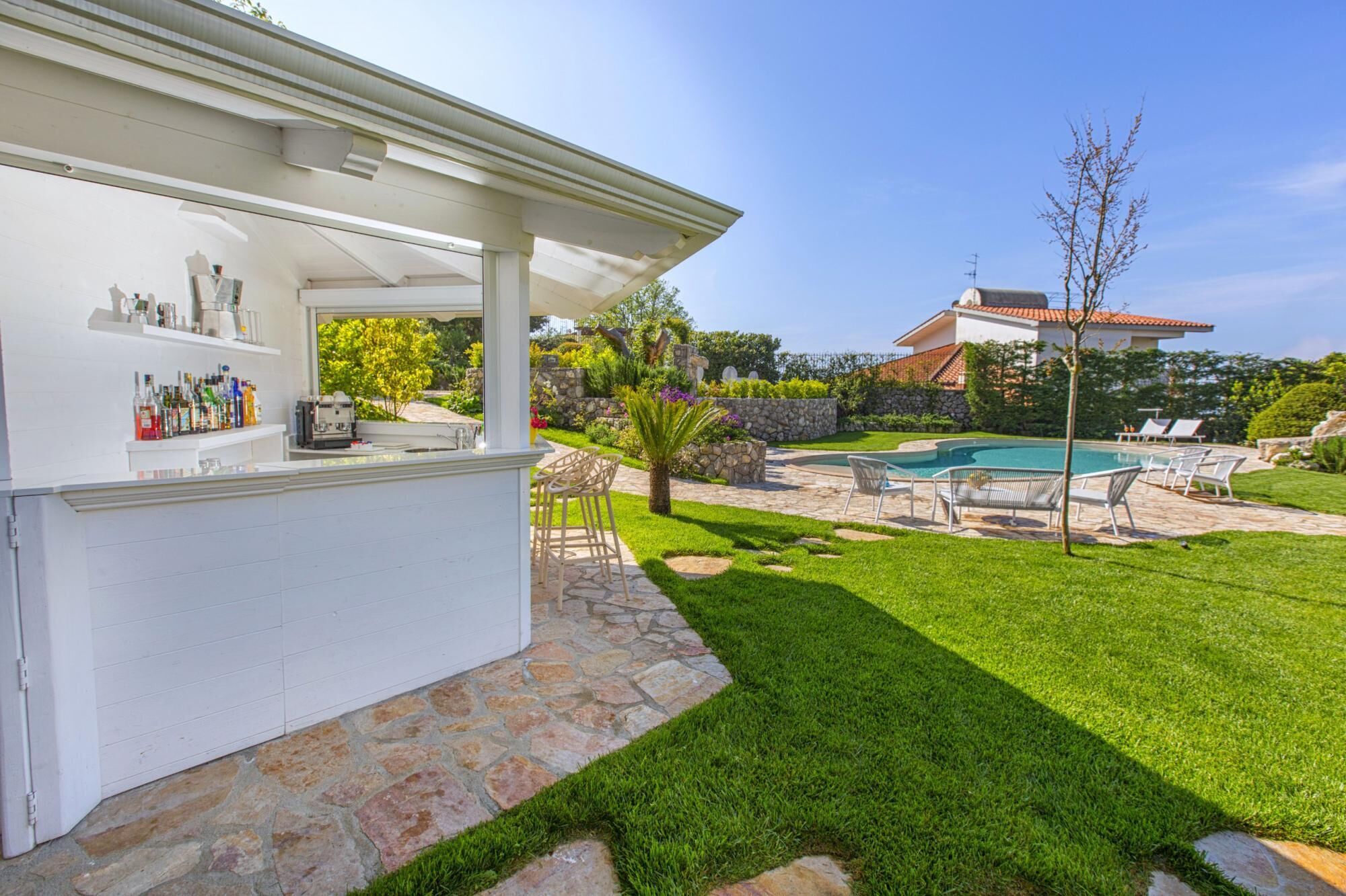 Ein Garten mit Pool, Bar und Sitzgelegenheiten im Freien.