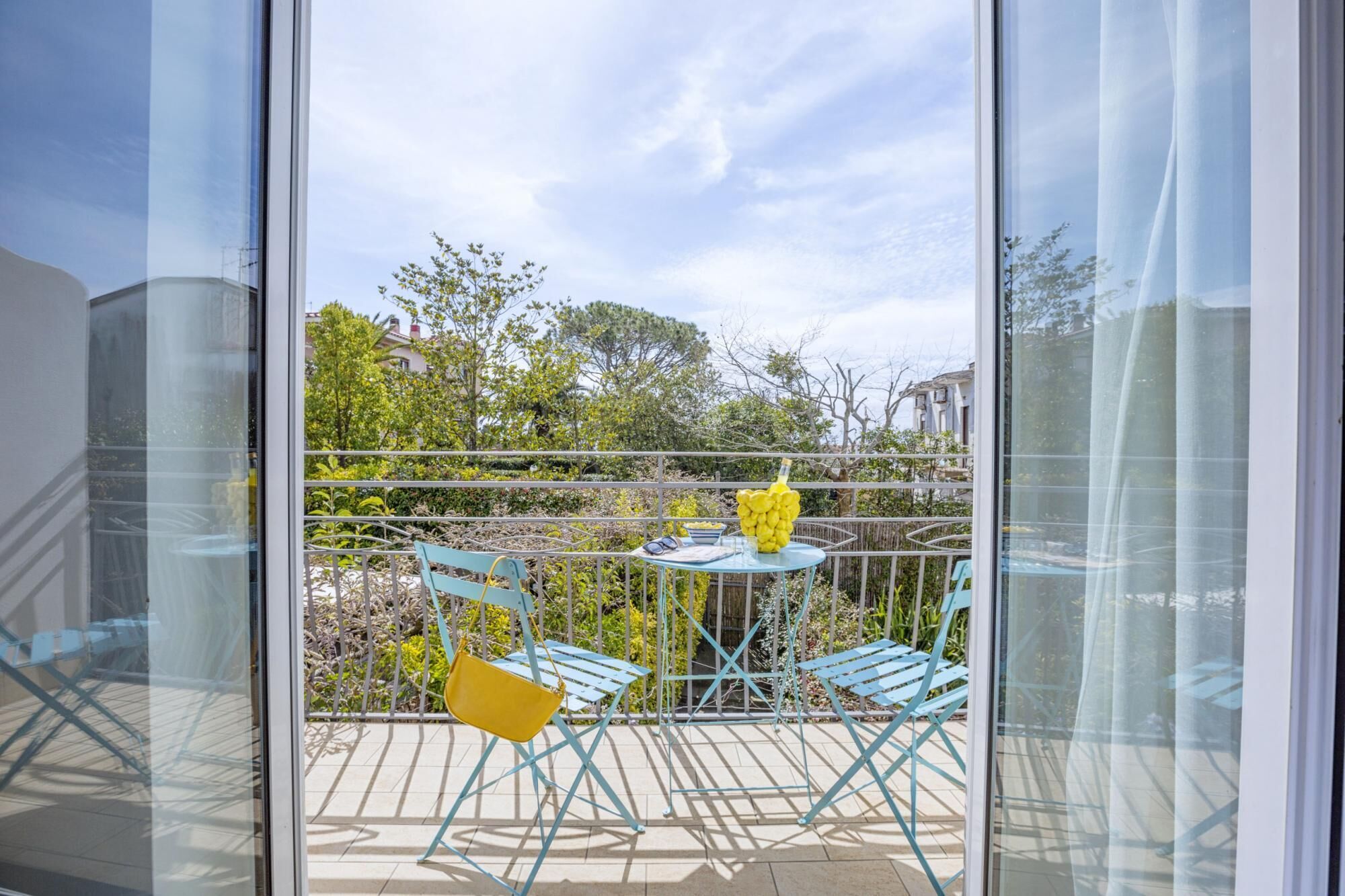 A balcony with a table, chairs, and a yellow bag.