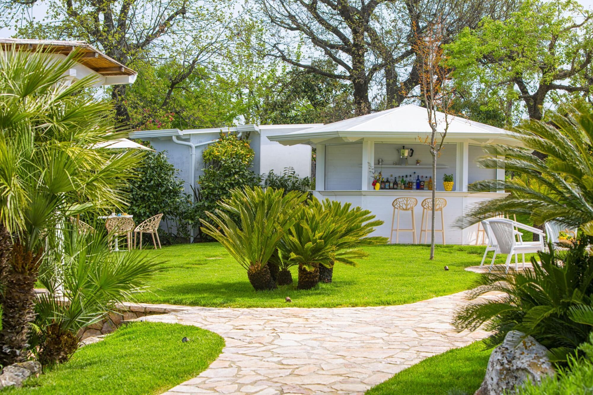 A patio area with a bar, stone pathway, and lush greenery.