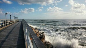 Une jetée s’avançant dans la mer, avec une rambarde d’un côté et une côte rocheuse de l’autre.