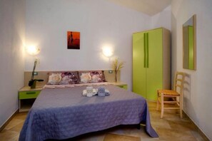 A bedroom with a bed, nightstands, a green wardrobe, a chair, and a painting on the wall. - MUSEDDU HOUSE 2 (Cardeddu)