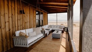 A wooden cabin with a white sofa and a coffee table, a view of the desert landscape through large windows. - Three Peaks Ranch (Westcliffe)