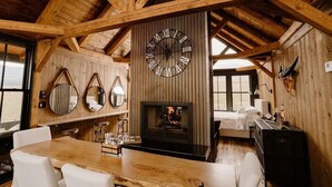 A rustic wooden interior with a large wall clock, mirrors, and a fireplace. - Three Peaks Ranch (Westcliffe)