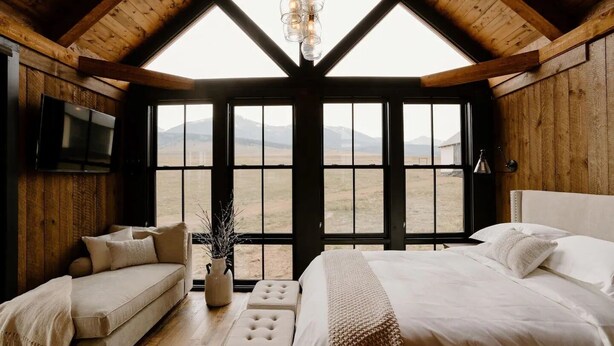 A room with a large bed, a sofa, and a TV mounted on the wall. - Three Peaks Ranch (Westcliffe)