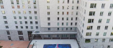 A multi-story building with a basketball court in the courtyard.
