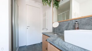 A bathroom with a white door, a marble countertop, a mirror, and a bottle of liquid soap.