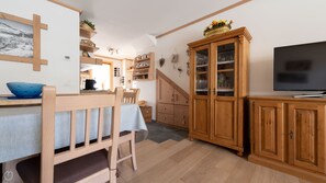 A cozy kitchen with wooden cabinets, a dining table, and a TV.