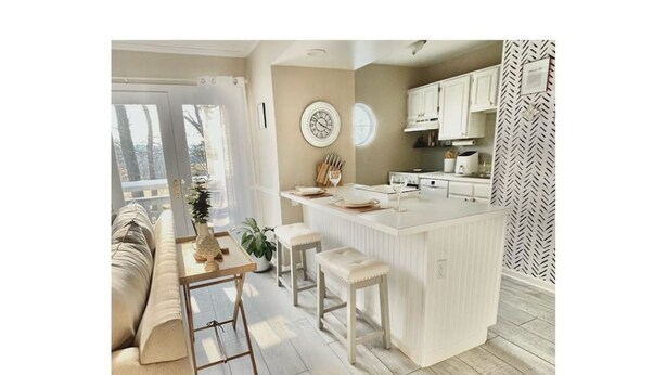 A modern kitchen with a central island, white cabinetry, and a herringbone-patterned wall.