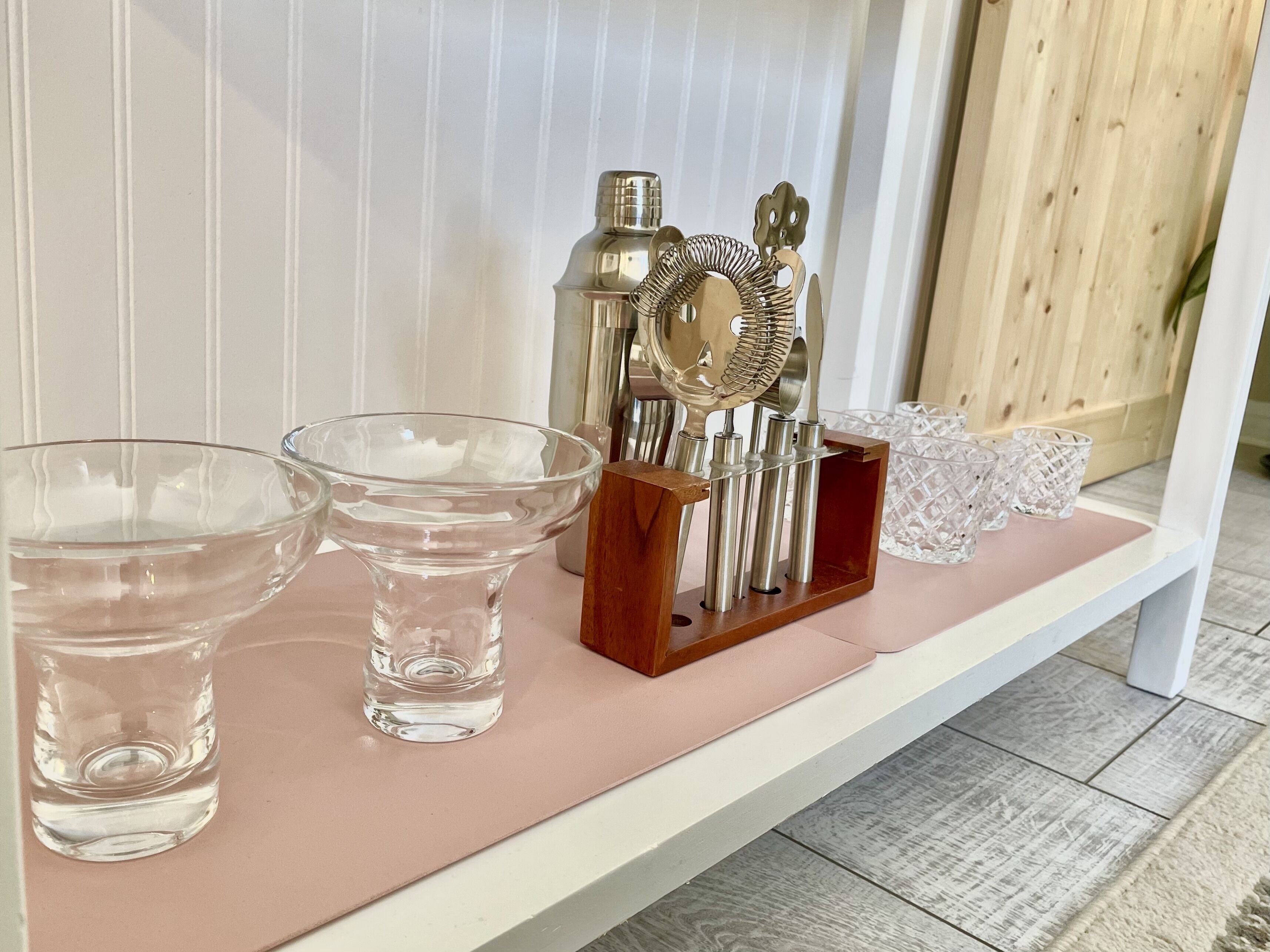 A shelf with glassware and a metal utensil set.