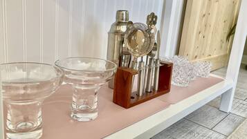 A shelf with glassware and a metal utensil set.
