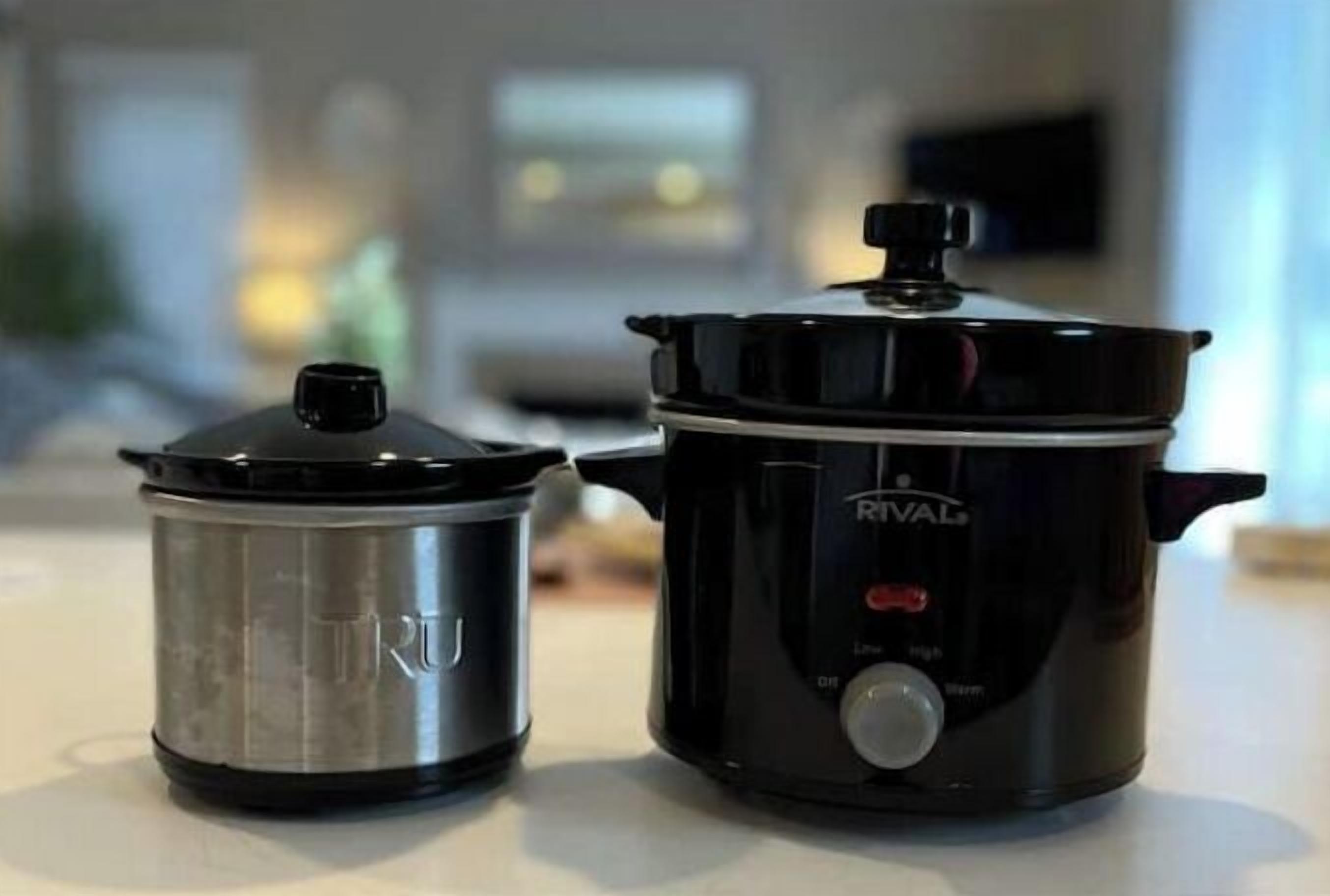 Une cuisine avec une mijoteuse noire et une casserole en acier inoxydable posée sur le plan de travail.