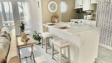 Una cocina moderna con una isla central, armarios blancos y un revestimiento de pared con motivo de espiga.