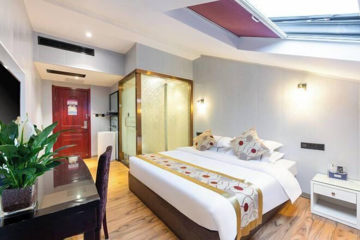 Een moderne hotelkamer met een bed, nachtkastje, stoel en een klein bureau met een plant.