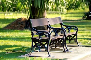 A park bench with a metal frame and wooden seat, located on a paved path.