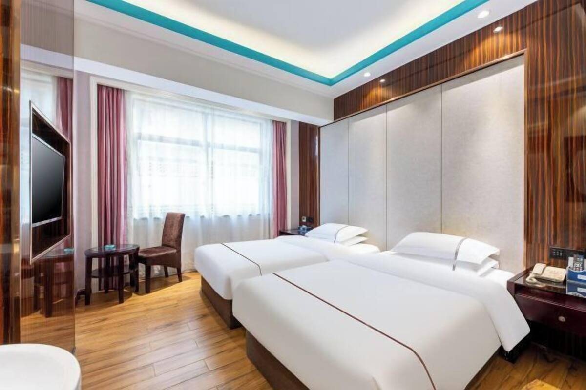 Een hotelkamer met twee bedden, een televisie, een bureau en een stoel.