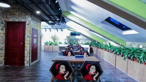 Een modern restaurant met hexagonale zitjes, een schuin dak en een rij groene planten langs de muur.