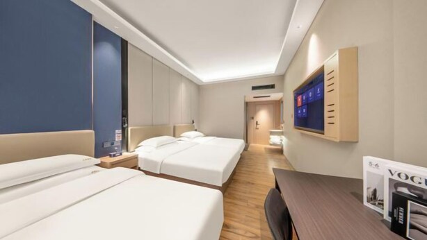 Een hotelkamer met twee bedden, een bureau, een televisie en een kledingkast.