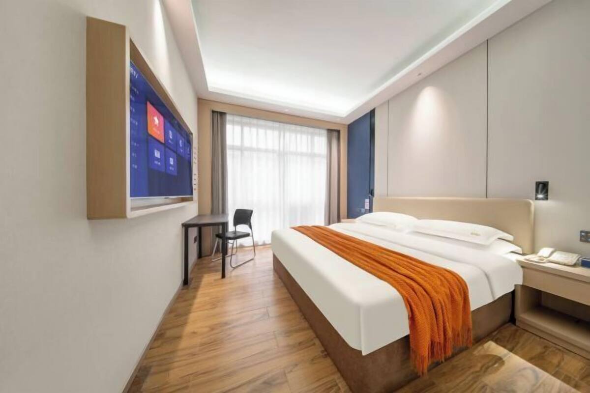 Een moderne hotelkamer met een groot bed, een bureau en een aan de muur bevestigde televisie.