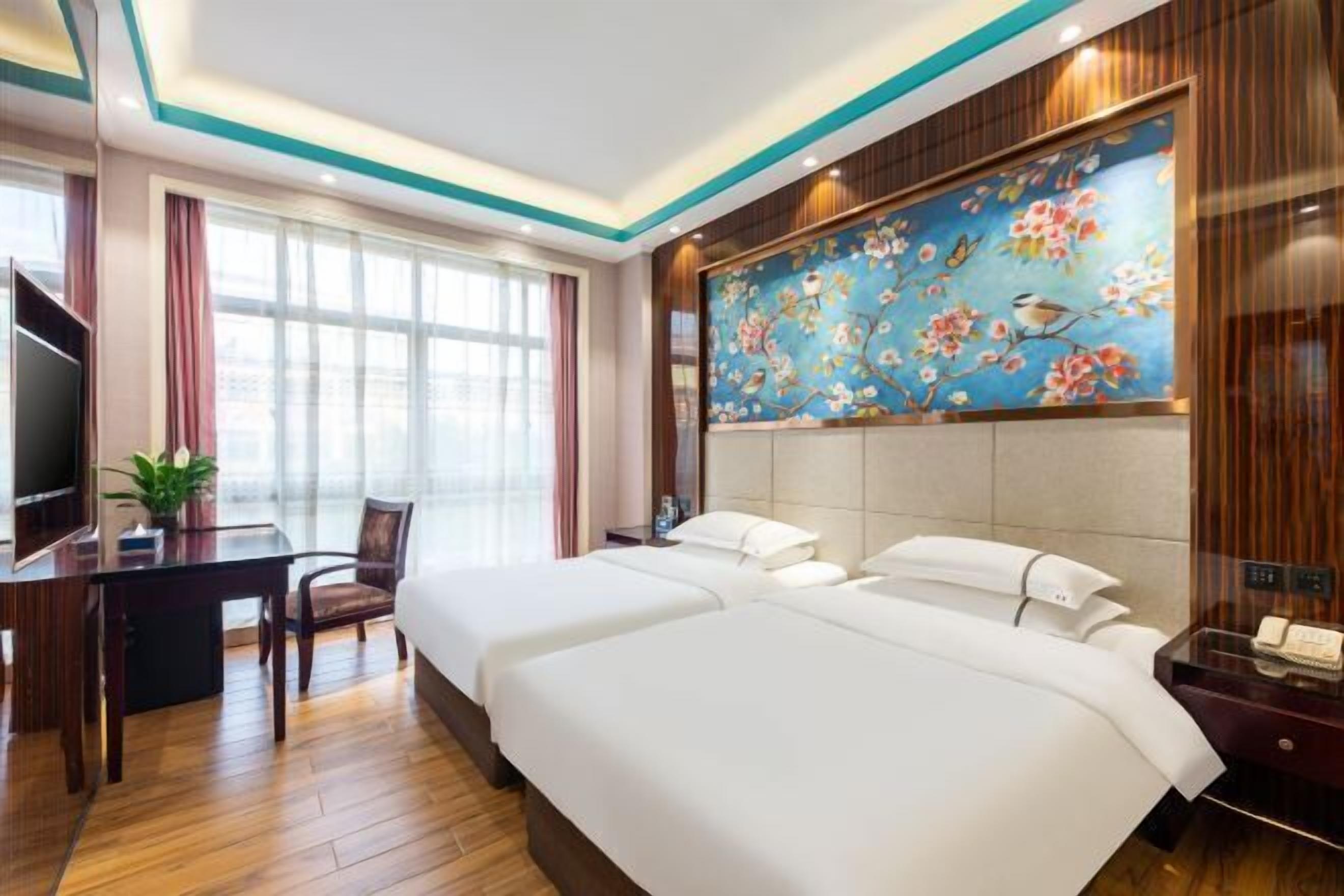 A hotel room with a large bed, a desk, and a TV.