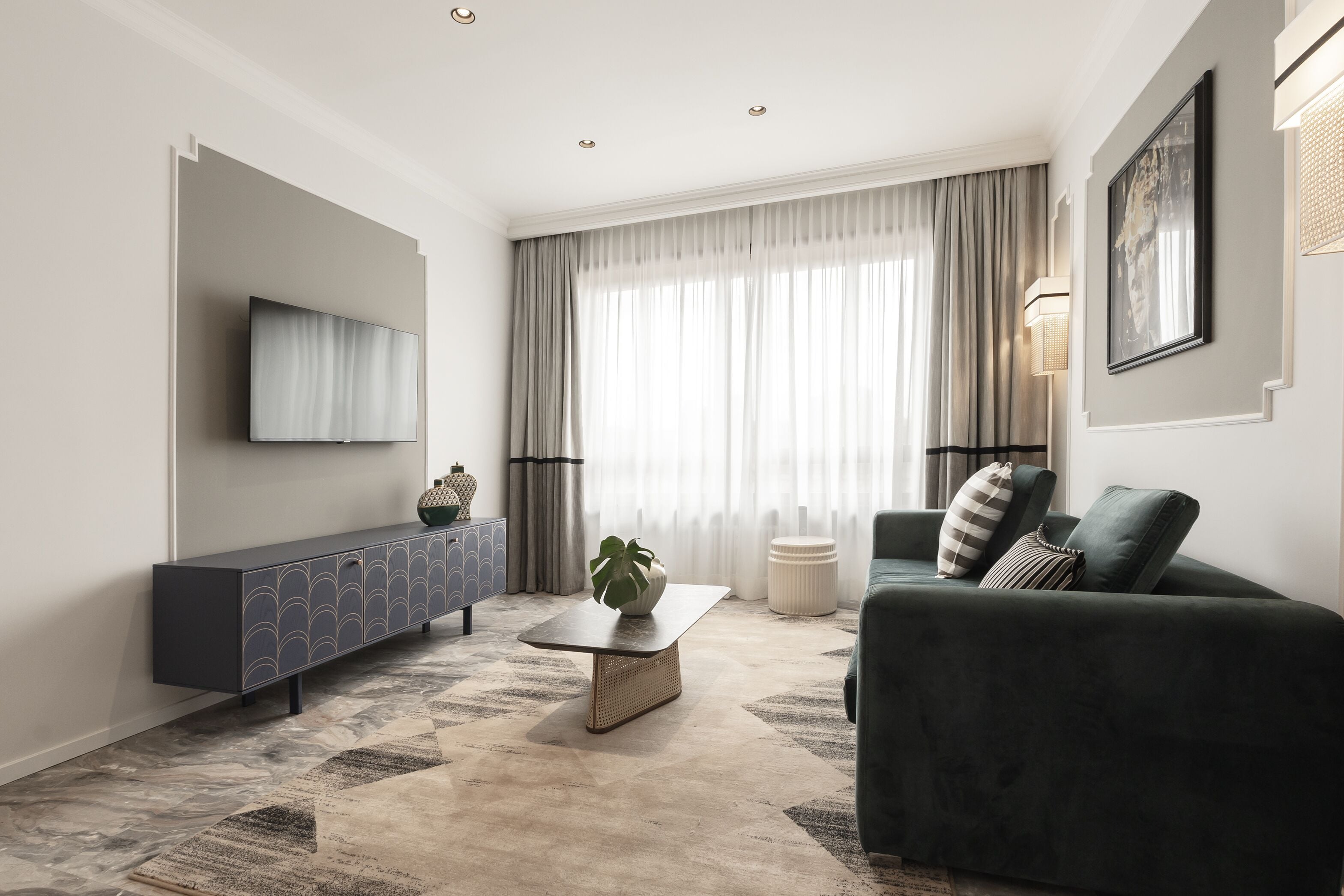 A modern living room with a sofa, a coffee table, and a TV mounted on the wall.