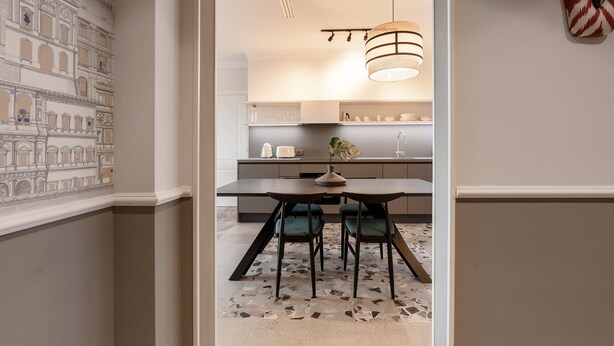 Una cocina moderna con comedor, que presenta una pared con diseño, una lámpara colgante y una planta en la encimera.