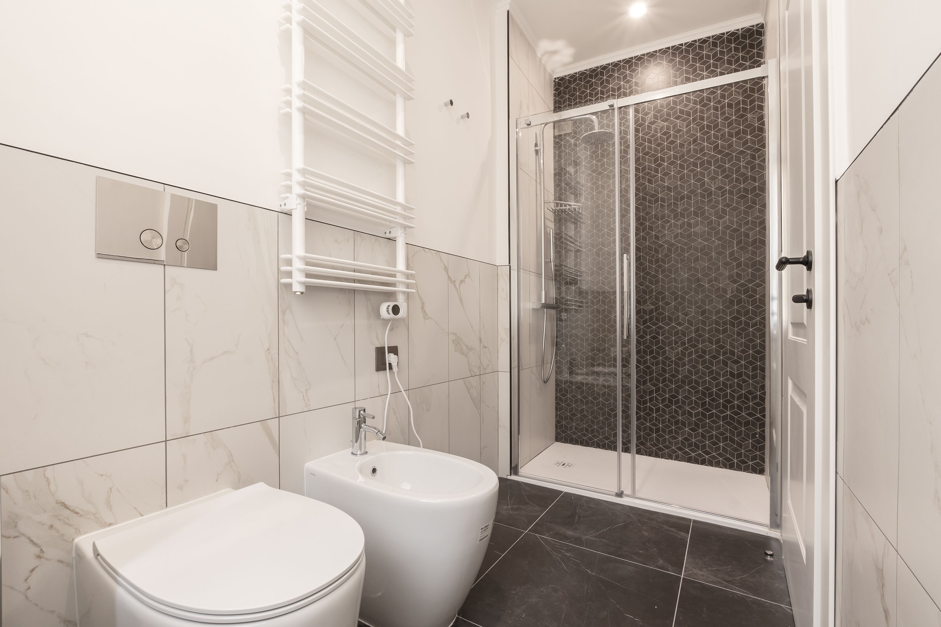 Un baño moderno con inodoro, bidé y zona de ducha con mampara de vidrio.