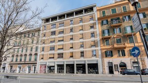 Un edificio de varios pisos con un local comercial en la planta baja, entrada visible y fachada orientada a la calle, con un cielo despejado arriba.