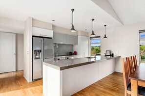 Una cocina moderna con una isla grande, electrodomésticos de acero inoxidable e iluminación colgante.