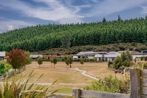 Zona residencial con casas, un campo cubierto de césped y un bosque denso al fondo.