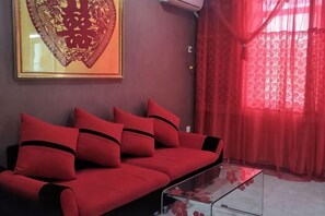 A red sofa with black accents, a glass coffee table, and a framed artwork on the wall. - Kingdom Hotel (Panjin)