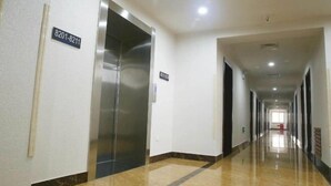 A hotel corridor with a shiny elevator, a sign with numbers, and a long hallway with doors on both sides. - Kingdom Hotel (Panjin)