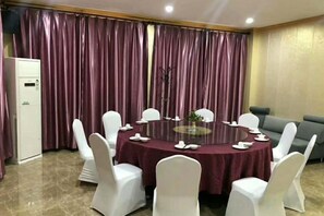 A conference room with a round table, white chairs, and a glass-top table. - Kingdom Hotel (Panjin)