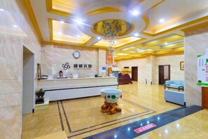 A hotel reception area with a marble floor, a reception desk, a clock, and a decorative plant. - Kingdom Hotel (Panjin)