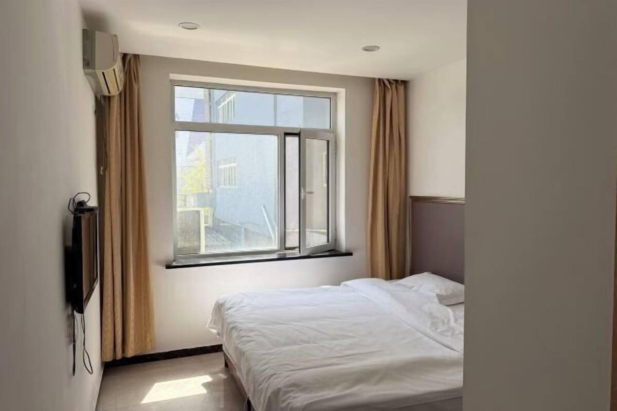 A bedroom with a bed, a window, and an air conditioning unit.