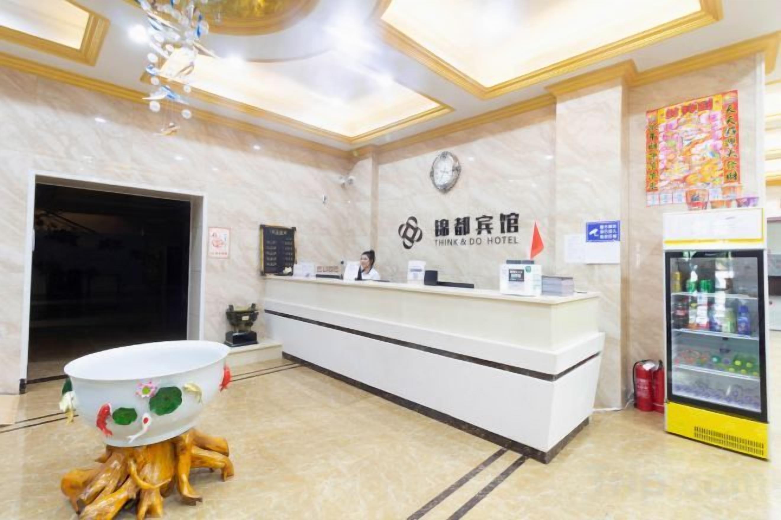 A reception desk with a clock, a signboard, and a refrigerator.