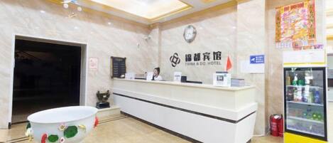 A reception desk with a clock, a signboard, and a refrigerator.