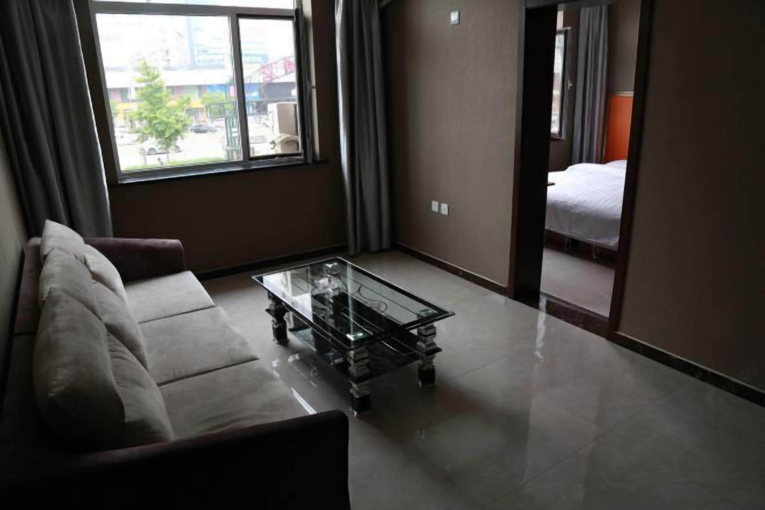 A hotel room with a glass-top coffee table, a sofa, and a bed.